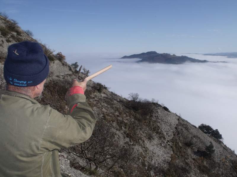 Foto invernale in cui l'amico Tonino indica le cime del monte Spugi e Rontana affiorare dalla nebbia.